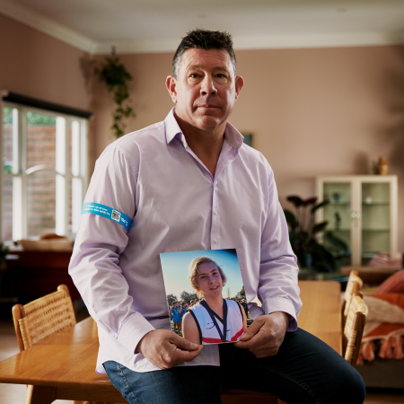 St Kilda AFL coach Brett Ratten, wears a Band Together armband while holding a photo of his son Cooper