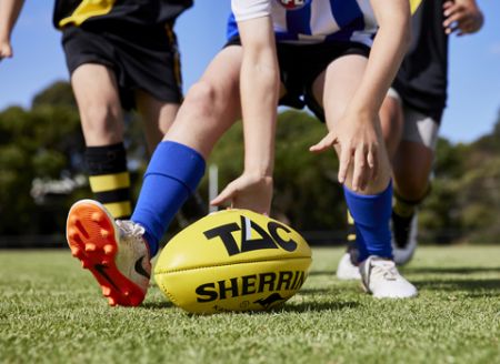 Australian rules football played on green grass.