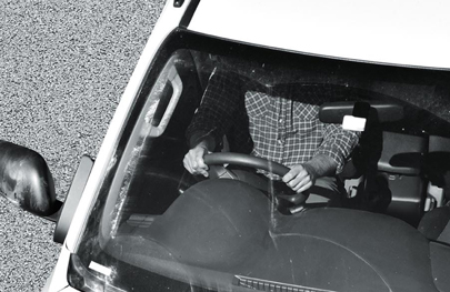 A person shown in their vehicle with their mobile phone on their lap