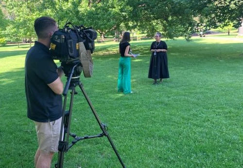 The TAC's Executive General Manager of Road Safety, Samantha Cockfield being interviewed by a woman while a camerman films. They are outside on a lawn in a garden space.