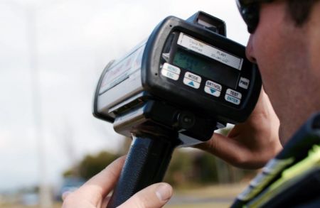 A close up of a police officer looking into a speed detector.