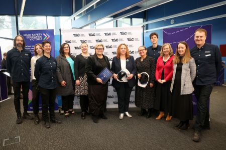A group of 12 people from Road Smart Interactive from Museums Victoria and the Transport Accident Commission standing in front of the TAC banner.