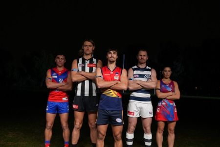 Four football players and one netball player standing arms crossed, wearing blue arm bands for the Road Safety Round. All wearing club colours standing against a dark background. 