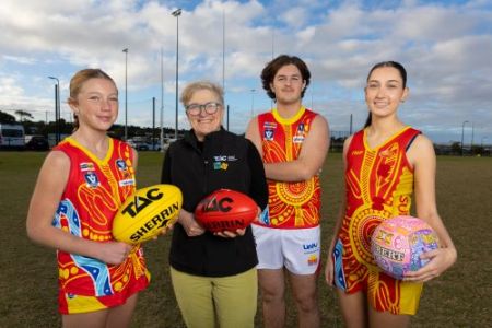Pictured on an AFL rules football oval from left, young female footballer holding football, TAC CEO Tracey Slatter holding a TAC football, young male footballer arms crossed, young female netballer holding a netball. All players wearing Surf Coast Suns Football and Netball Club. Club. 